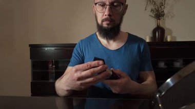 Şık bir adam sakalını elektrikli traş makinesi kullanarak dikkatlice buduyor. Kişisel bakım rutinini gösteriyor. Bu video erkek güzelliğini ve özbakımını ön plana çıkarıyor..