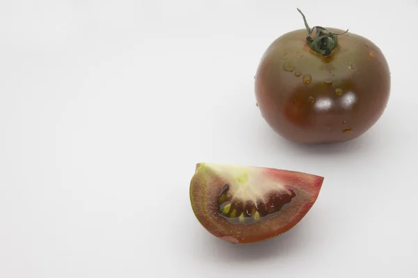 Kumato, tomate escuro com fatia — Fotografia de Stock