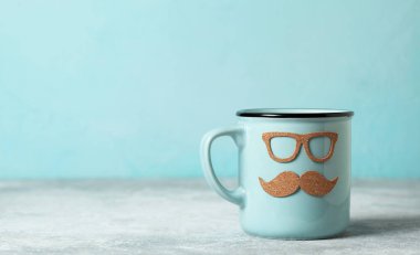 Babalar Günü hediyesi konsepti. Mavi arka planda bıyıklı ve gözlüklü mavi kupa.