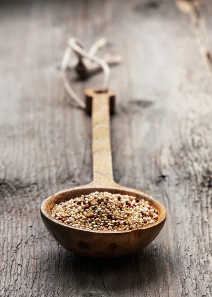 Quinoa in een lepel op een houten achtergrond — Stockfoto