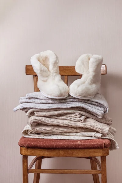 Sheepskin slippers, stack of warm clothes — Stock Photo, Image