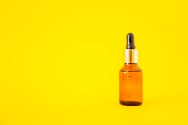 Parlak sarı arka planda serumu olan kozmetik şişeleri. Kozmetik ve güzellik kavramı.