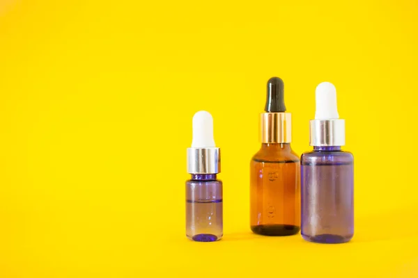 Frascos cosméticos con suero sobre fondo amarillo. Cosmetología y concepto de belleza. —  Fotos de Stock