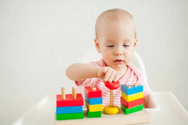 Holčička si hraje se vzdělávací hračkou - pestrobarevnou dřevěnou pyramidou. Rozvoj jemných motorických dovedností a logického myšlení — Stock fotografie