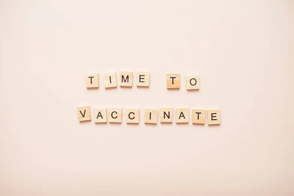 Čas na očkování z dřevěných bloků na světle růžovém pozadí — Stock fotografie