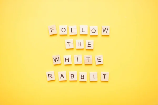 Fráze sledovat bílý králík vyrobený z dřevěných bloků na světle žlutém pozadí — Stock fotografie