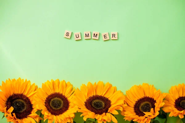 Inscriptie van houten blokken zomer. Heldere sappige zonnebloemen op een groene achtergrond. Indeling. — Stockfoto