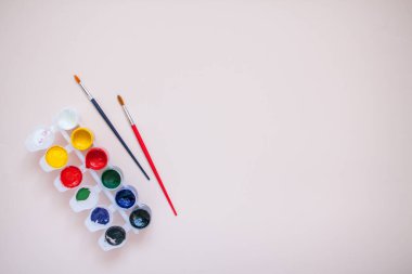 Açık pembe arka planda parlak boyalar ve iki fırça. Çizim için hazırlama