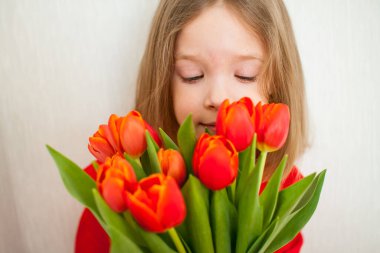 Parlak kırmızı balıkçı yakalı güzel kız elinde bir buket kırmızı lale tutuyor.