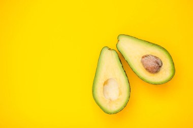 Parlak sarı bir arka planda olgun, güzel bir avokado.