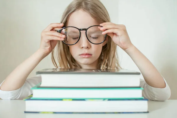 Mała dziewczynka w okularach odrabia lekcje, czyta książki.. — Zdjęcie stockowe