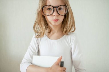 Gözlüklü küçük kız ev ödevi yapıyor, kitap okuyor..