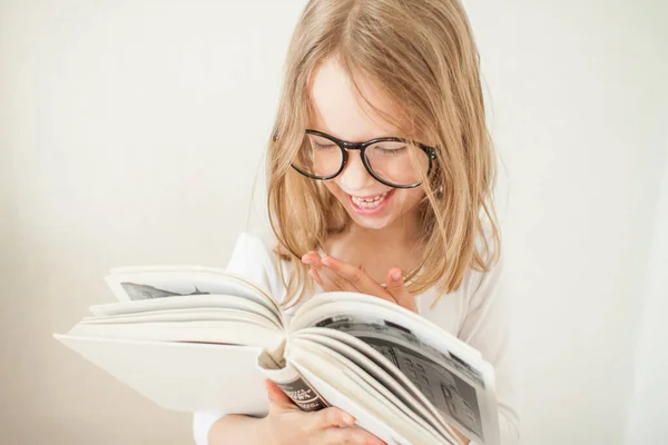 Mała dziewczynka w okularach odrabia lekcje, czyta książki.. — Zdjęcie stockowe