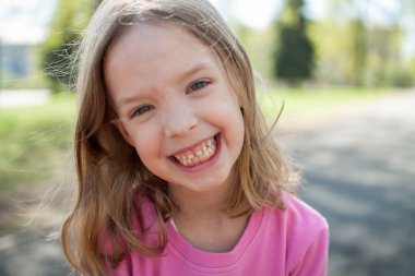 Küçük mutlu kız yazın parkta yürüyor.