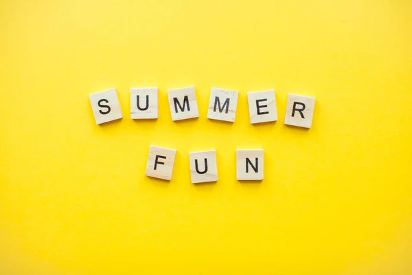 The inscription from wooden cubes summer fun on a bright yellow background — Stock Photo, Image