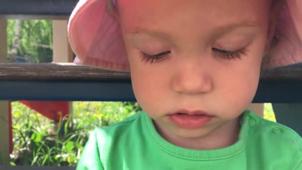Ein kleines Mädchen mit rosa Panamahut spaziert und erkundet die Natur an einem sonnigen Sommertag. — Stockvideo