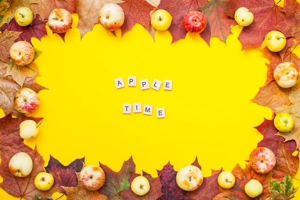Inscripción de bloques de madera hora de la manzana. Marco hecho de hojas de arce de otoño rojo y naranja y manzanas de jardín sobre un fondo amarillo brillante. Disposición. — Foto de Stock