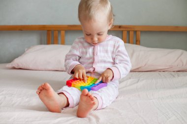 Küçük kız son moda duyusal oyuncaklarla oynuyor. Kız renkli gökkuşağı yumuşak silikon kabarcıklarına bastırıyor. Stres ve anksiyete rahatlaması.