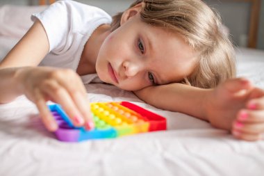 Küçük kız son moda duyusal oyuncaklarla oynuyor. Kız renkli gökkuşağı yumuşak silikon kabarcıklarına bastırıyor. Stres ve anksiyete rahatlaması.