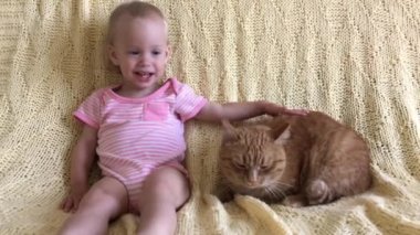 Küçük kız büyük kızıl bir kediyle oynuyor.