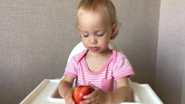 Kleines Mädchen schmeckt und isst saftige Nektarine mit Freude und Interesse — Stockvideo