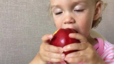 Küçük kız zevk ve ilgiyle sulu nektarin yer ve tadar.