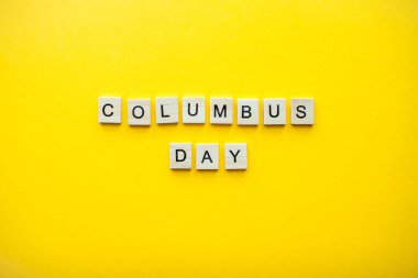 Parlak sarı bir zemin üzerinde tahta bloklardan yazıt kolomb günü