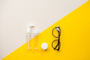 Parlak sarı bir arka plan. Kozmetik kavanozları ve gözlükler. Seyahat seti