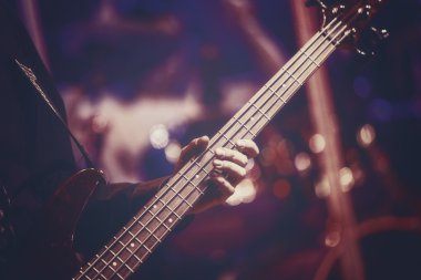 Close up view of guitarist hand playing bass guitar clipart