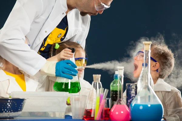 Дети с сумасшедшим профессором проводят научные эксперименты в лаборатории — стоковое фото