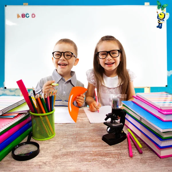 Dos niños en la mesa en el aula en la lección —  Fotos de Stock