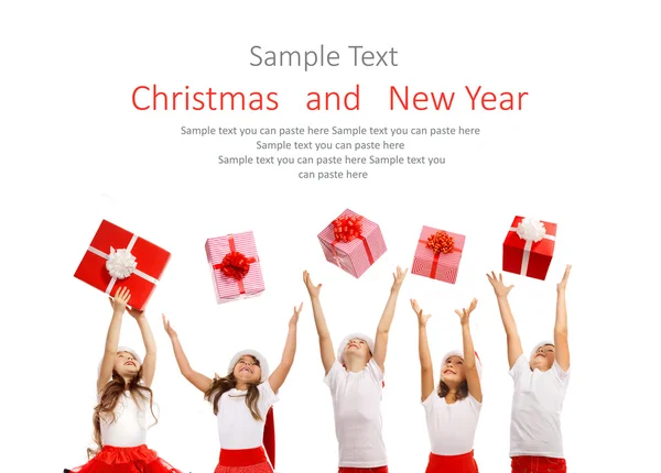 Group of happy kids in Christmas hat catching gift boxes — Stock Photo, Image