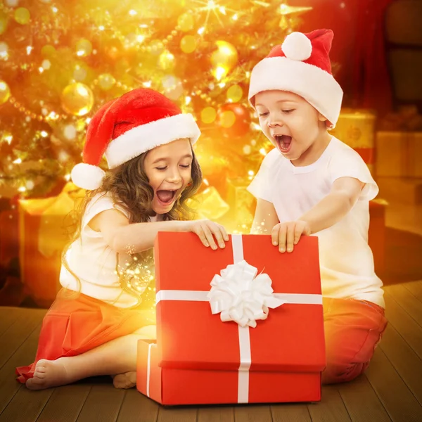 Happy kids in Santa hat opening a gift box — Stock Photo, Image