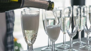 Garson bardağa şampanya dolduruyor.