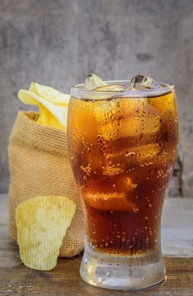 Cola con ghiaccio e patatine su fondo di legno . — Foto Stock