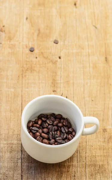 Granos de café en taza sobre un fondo wod . —  Fotos de Stock