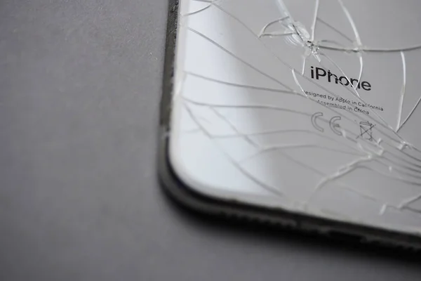 Blagoveschensk, Rusya - 30 Eylül 2020. Gri arkaplandaki çatlaklı ve yazılı iPhone 'lu akıllı telefonun arka kapağını kapat..