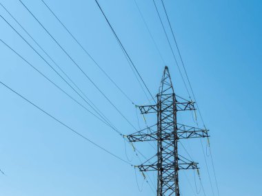 Mavi gökyüzüne karşı yüksek voltaj iletim kulesi hattı, alt görünüm.