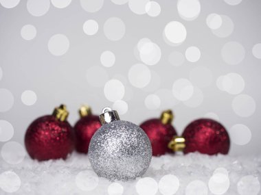 Noel ağacında bir gümüş top ve arkasında dört kırmızı top, arka planda bir bokeh, üzerinde bir yazıt için bir yer var..