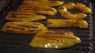 Sarı dolma biber parçaları elektrikli ızgarada kızarır ve ters döner, yakın plan..