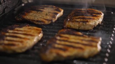 İyi pişmiş domuz eti elektrikli ızgaradan silikon maşayla çıkartılır..