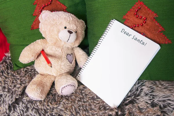 Little plush bear toy with pencil and blank notebook on a sofa. — Stock Photo, Image