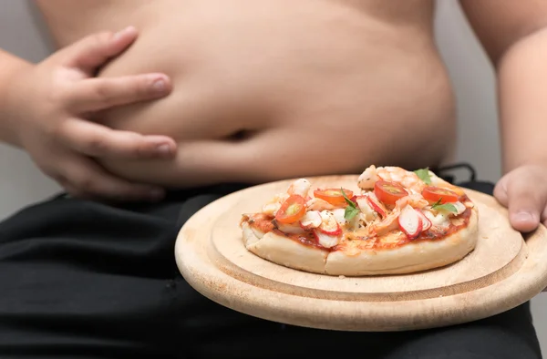 Pizza en plato de madera con fondo de niño gordo obeso — Foto de Stock