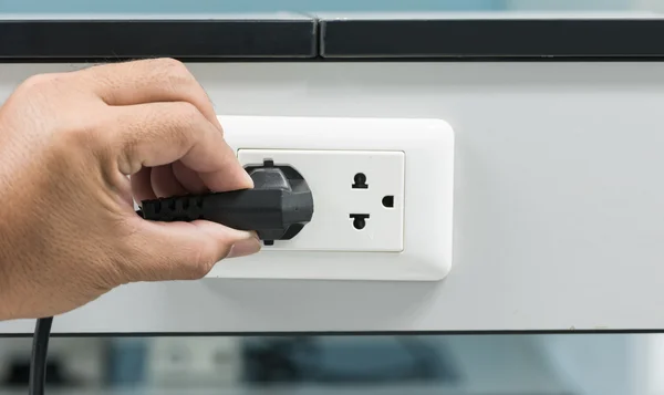 hand unplugging a plug from a socket