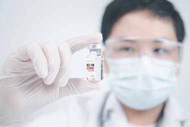 Coronavirus aşısı COVID-19 'un geliştirilmesi ve yaratılması. Steteskoplu genç bir doktor beyaz arka planda COVID-19 aşısı tutuyor. Aşı Coronavirus 'a karşı savaş kavramı