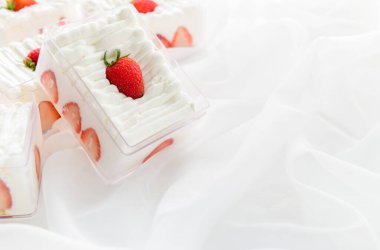 Kumaş arka planı ve kopyalama alanı olan plastik kutuda çilekli pasta, en az pasta ve fırın konsepti