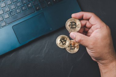 Siyah arka planda Bitcoin ve laptop tutan bir iş adamı. İnternet bankacılığı ve uluslararası ağ ödemeleri için elektronik sanal para, Para Birimi Teknolojisi İnternet Konsepti.