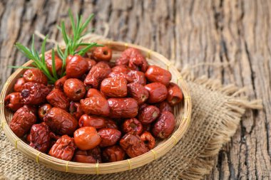 Dried Jujube, Chinese dried red date fruit in bamboo basket on old wood background,herbal fruits. It have more vitamin C Which helps fight free radicals And stimulate the immune system clipart