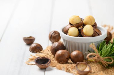 Beyaz ahşap arka planda beyaz fındıklı kavrulmuş Macadamia fındığı, tatonoidler ve tocotrienollerle dolu ve kalp dostu doymamış yağlar zengin.