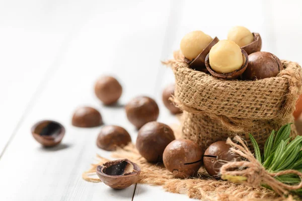 Dry Roasted Macadamia Nut in sack on white wood background, Macadamia nuts are loaded with flavonoids and tocotrienols and rich in heart-healthy monounsaturated fats